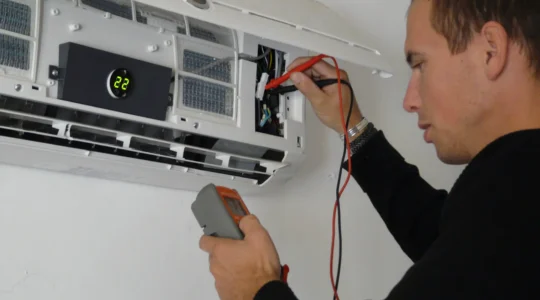 Technicien installant une unité murale de climatiseur réversible dans un salon moderne
